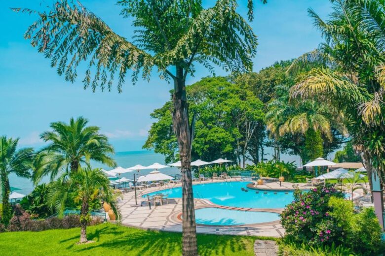 Lake Kivu waterfront hotel with palm trees, swimming pool and sun loungers overlooking the lake – perfect for Rwanda’s scenic stays guide by Ebenezer Hotel Apartments.